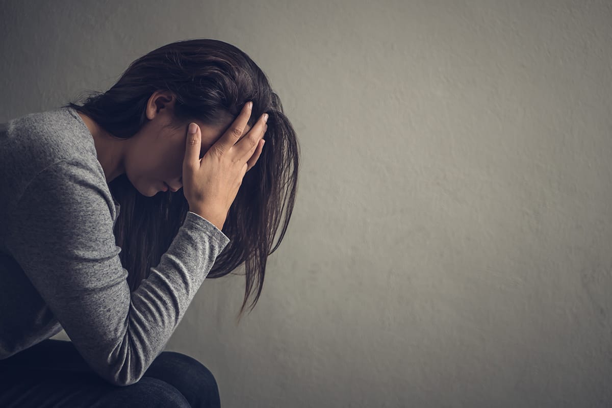 Juniper Avenue Medical Centre | Mental Health Services Woman sitting with her head in her hands, looking distressed